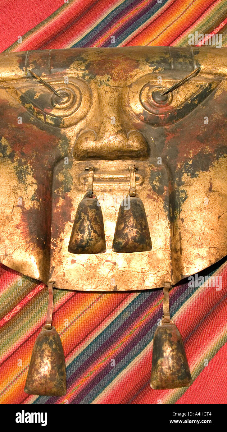 Handmade golden metal mask Stylized face with its teardrop eyes and linear mouth Handicraft from Peru Andean fabric Stock Photo