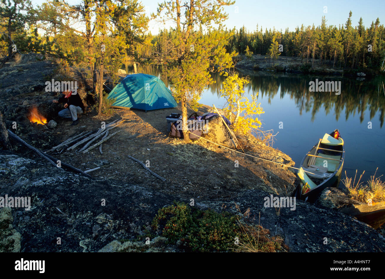 Man at campfire on a lakeshore, Northwest Territories, Canada Stock Photo