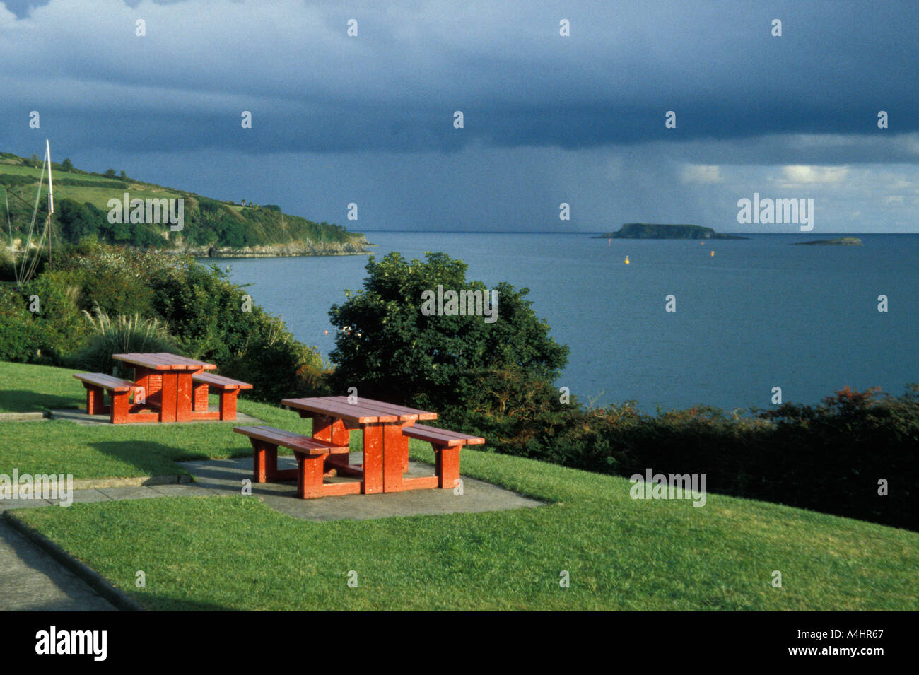 View of the sea with two red benches and tables Glandore County Cork