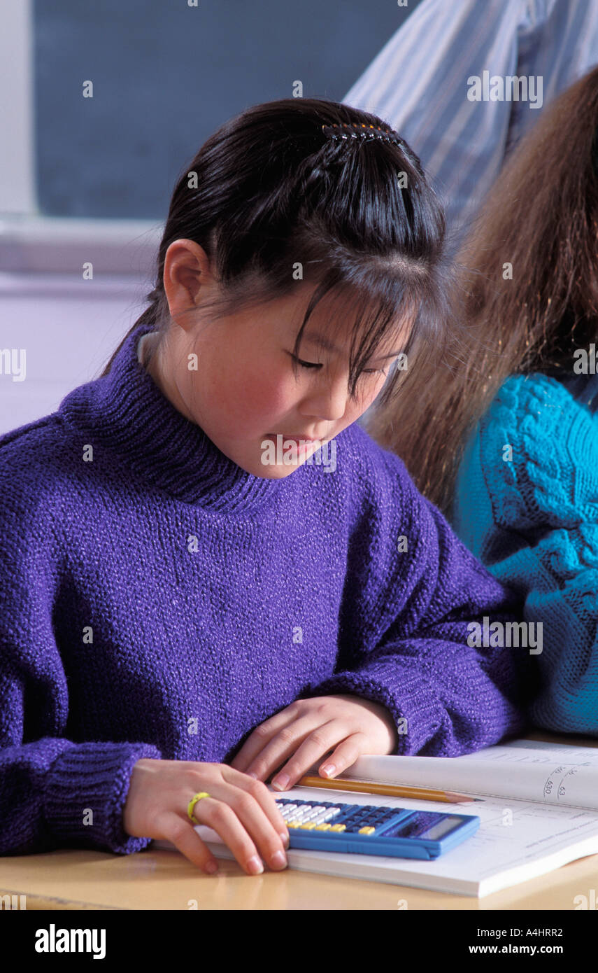 Asian American female student using calculator to do math work in class Stock Photo