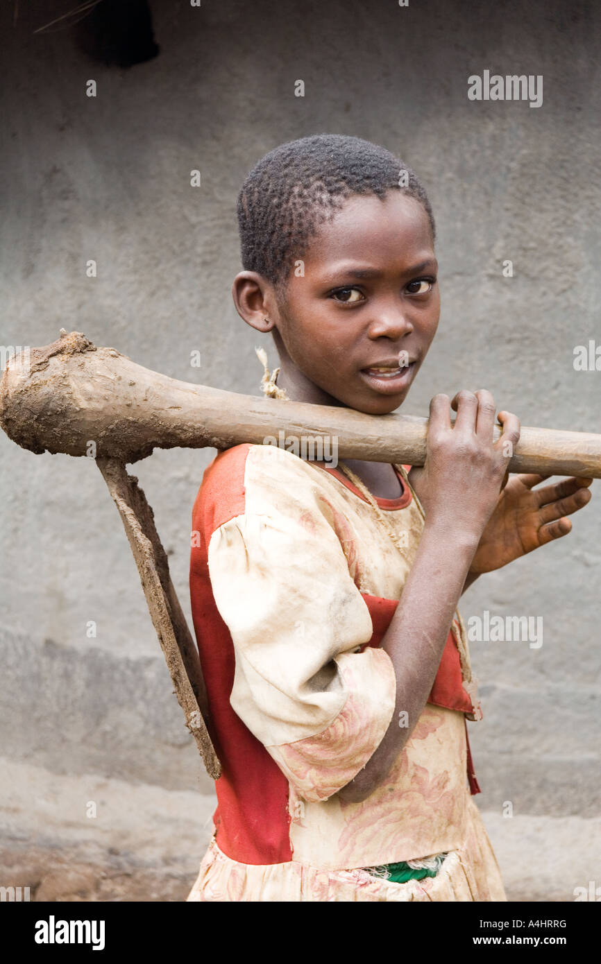 A young girl carrying a heavy mattock or Khasu hoe in the