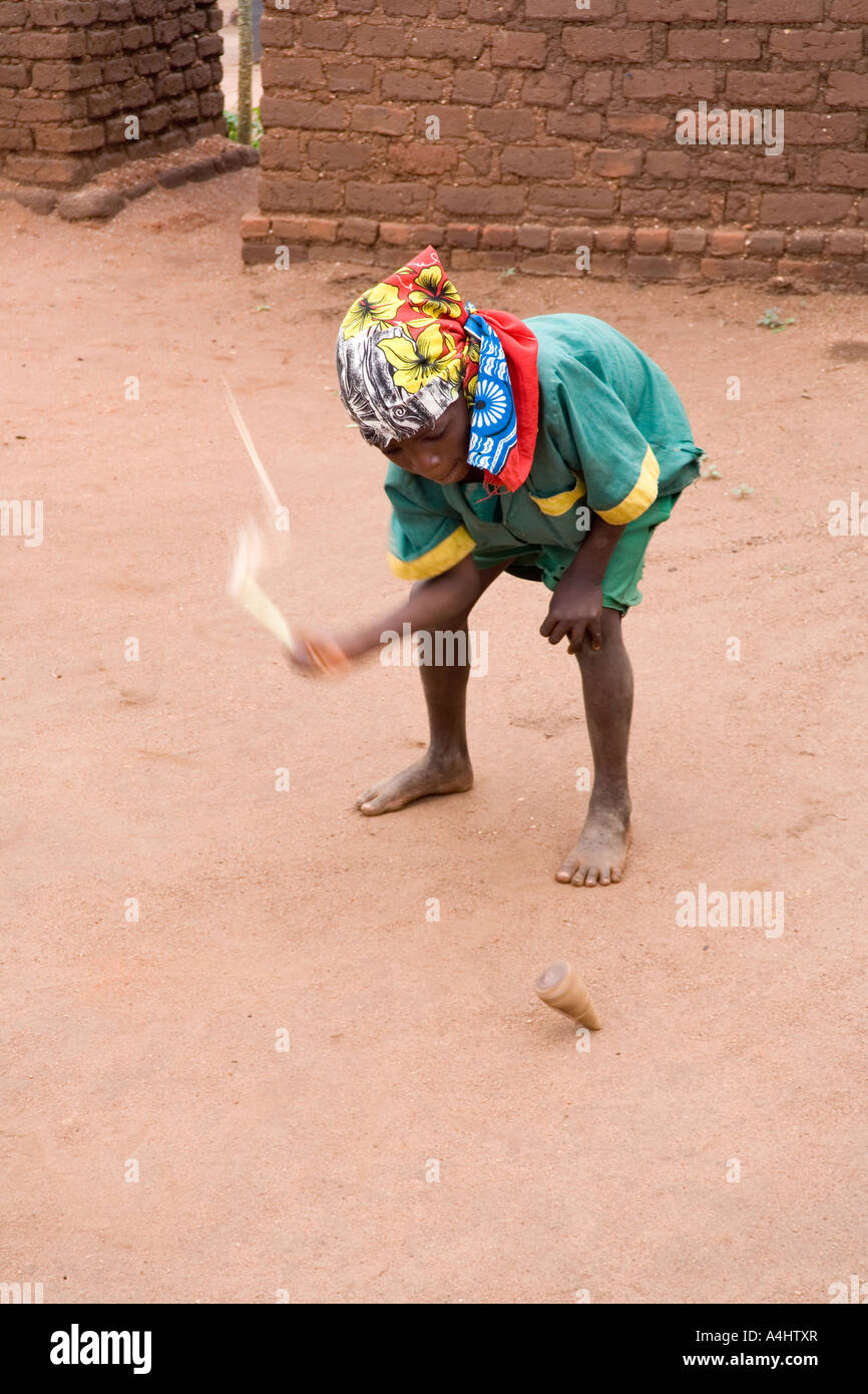 Boy playing with a homemade whip and spinning top in the village of