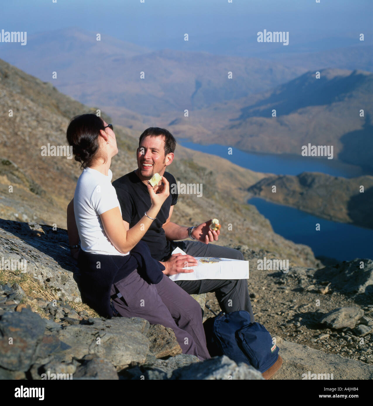 Hikers eating apples taking a rest and  looking at a map while walking up to Mount Snowdon in spring Snowdonia National Park Wales UK KATHY DEWITT Stock Photo