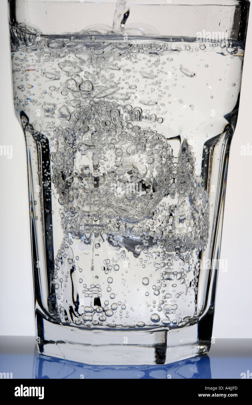 fizzy Water poured into glass with ice cubes Stock Photo - Alamy