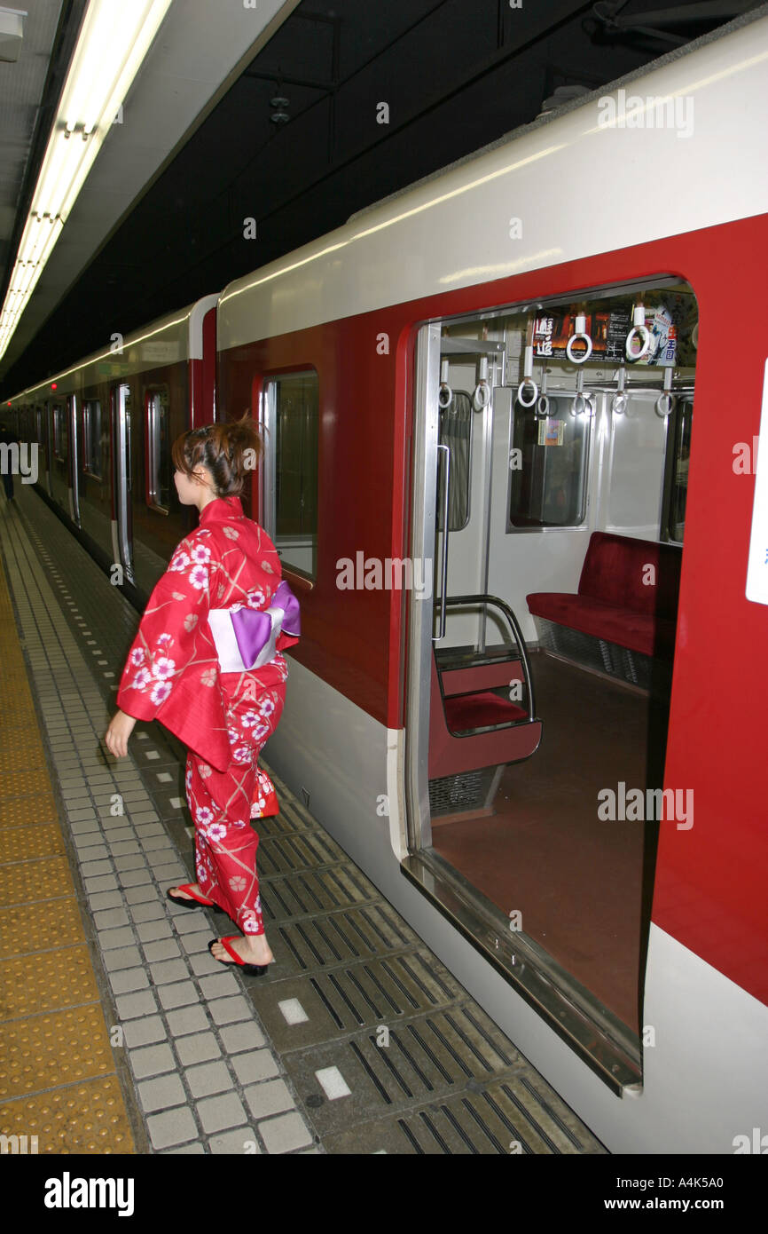 Beautiful young Japanese woman wearing a bright red kimono exits the train in Osaka Japan Asia Stock Photo