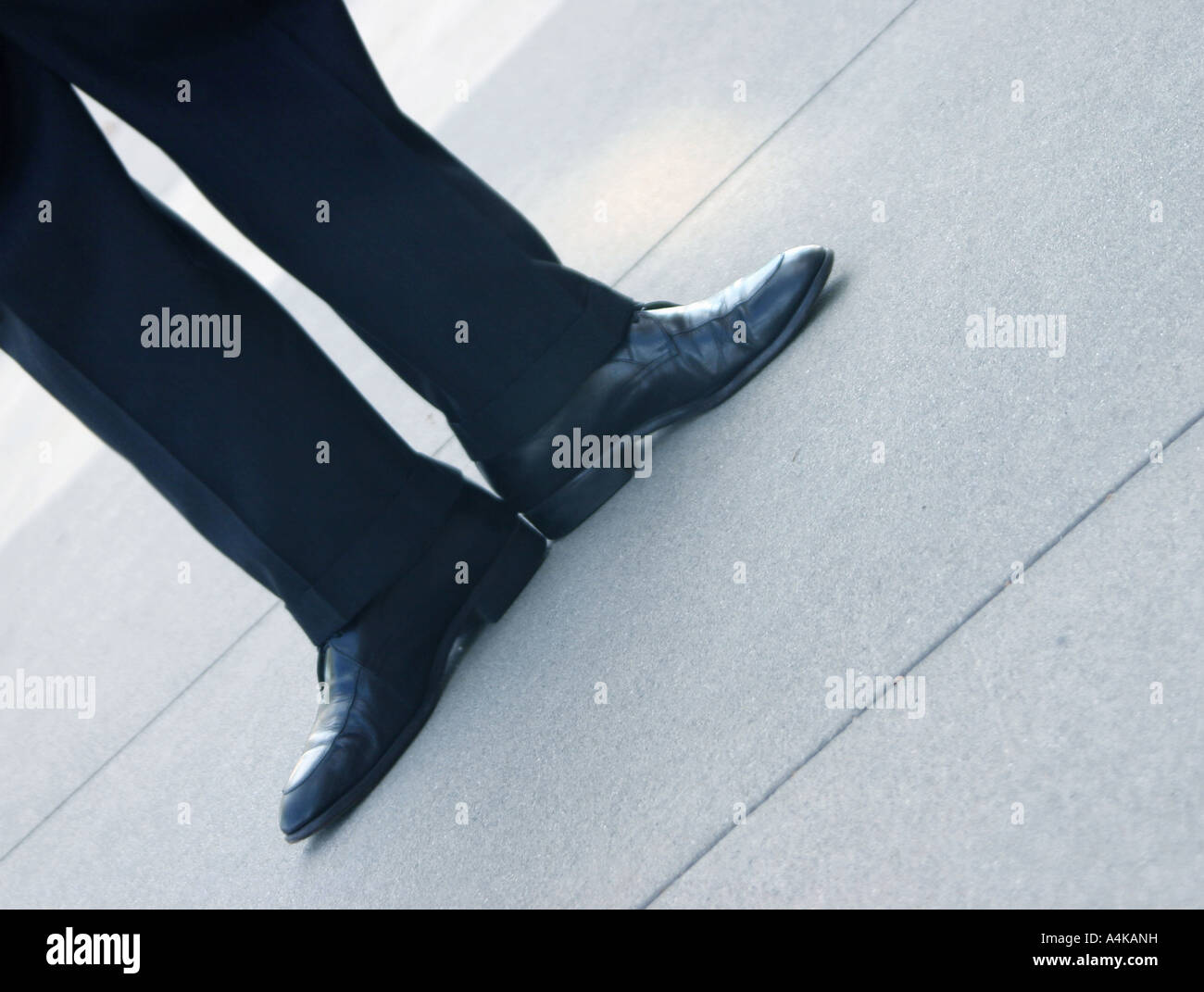 Business man has his feet pointed out in opposite directions on the concrete floor Stock Photo