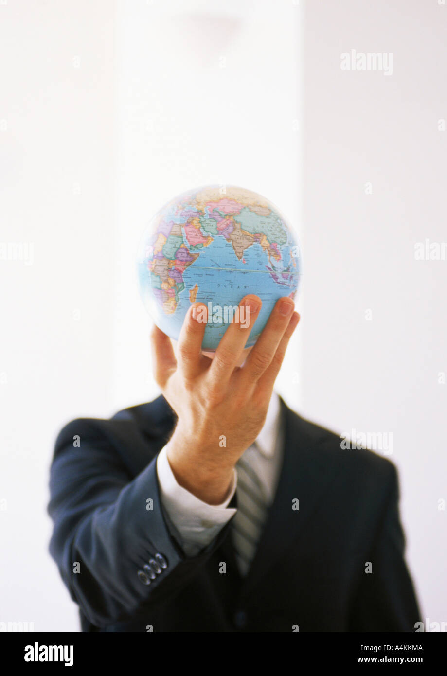 Businessman holding out globe, hiding man's face Stock Photo