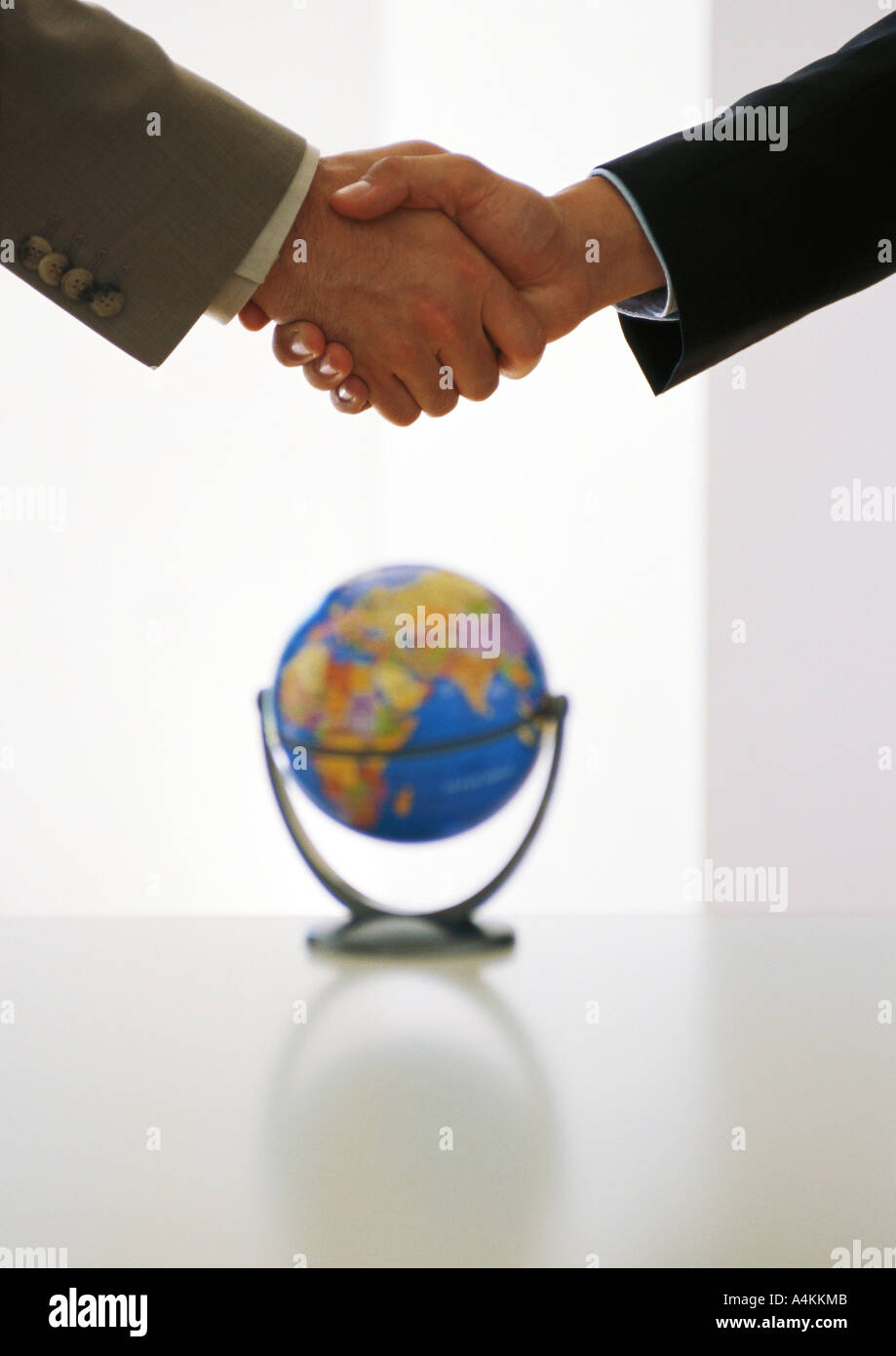 Two businessmen shaking hands above globe Stock Photo