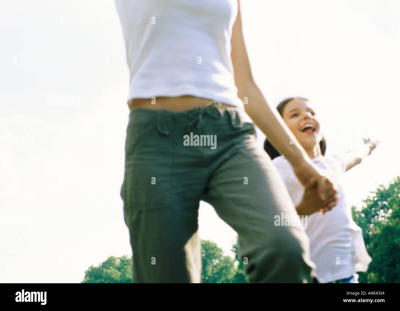 Woman and child holding hands and running outside Stock Photo - Alamy