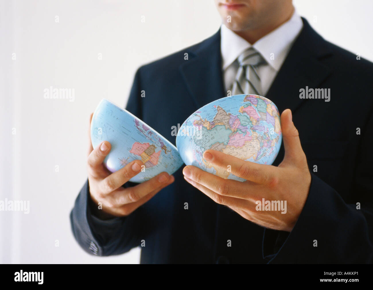 Businessman holding globe halves Stock Photo
