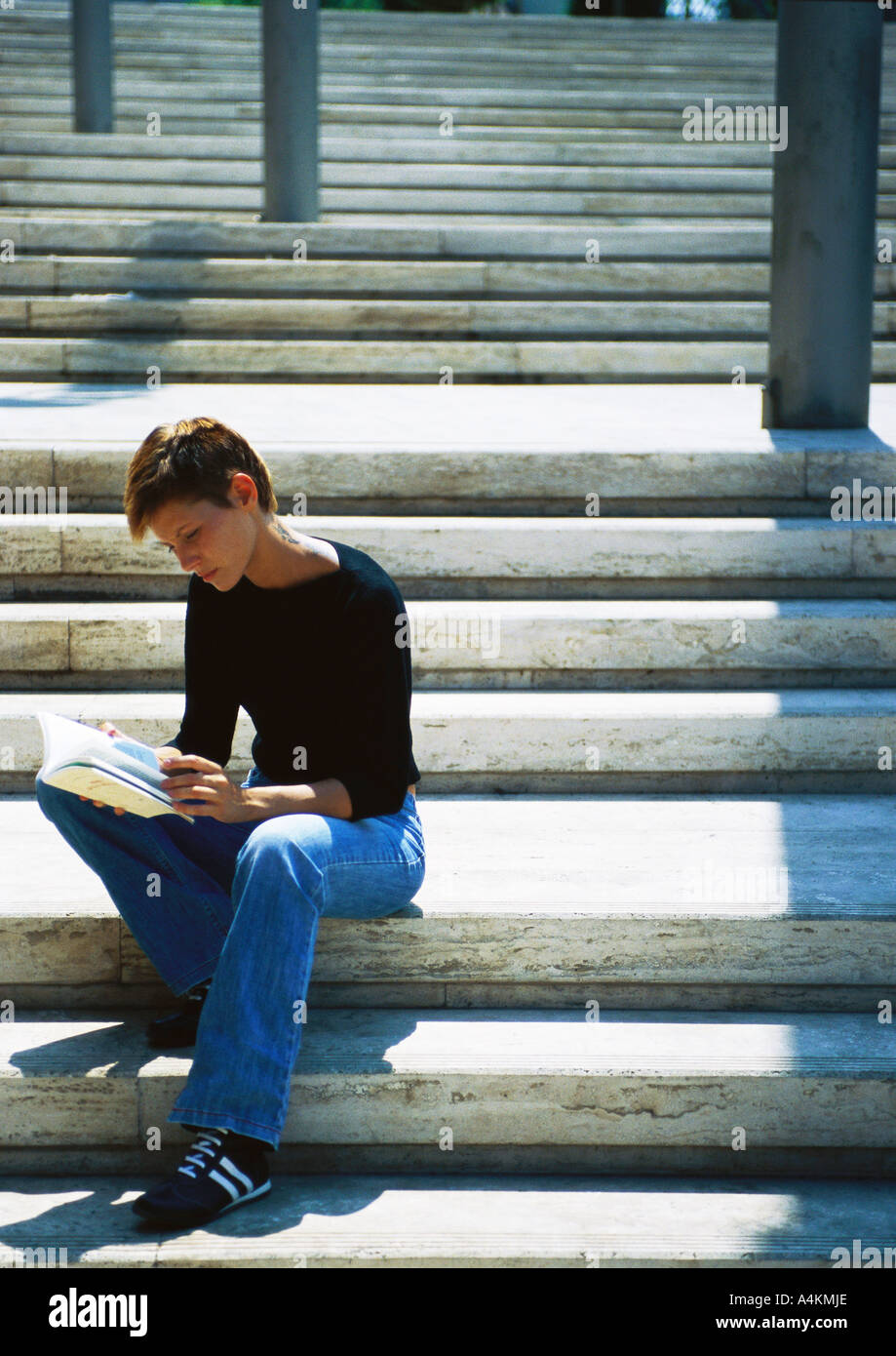 Woman sitting on stairs, reading Stock Photo