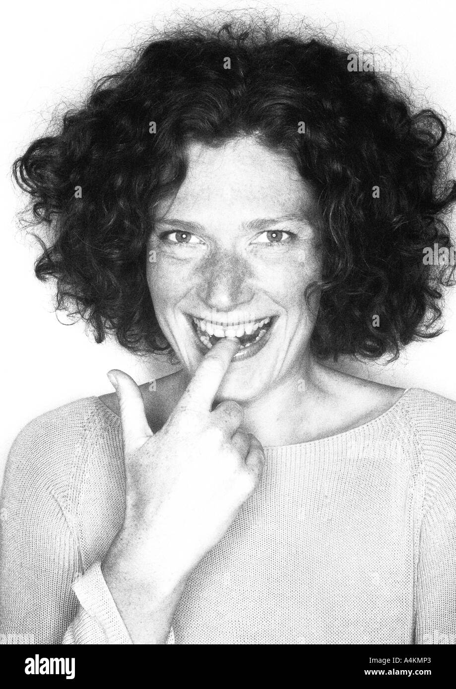 Woman smiling with finger in mouth, portrait, b&w. Stock Photo