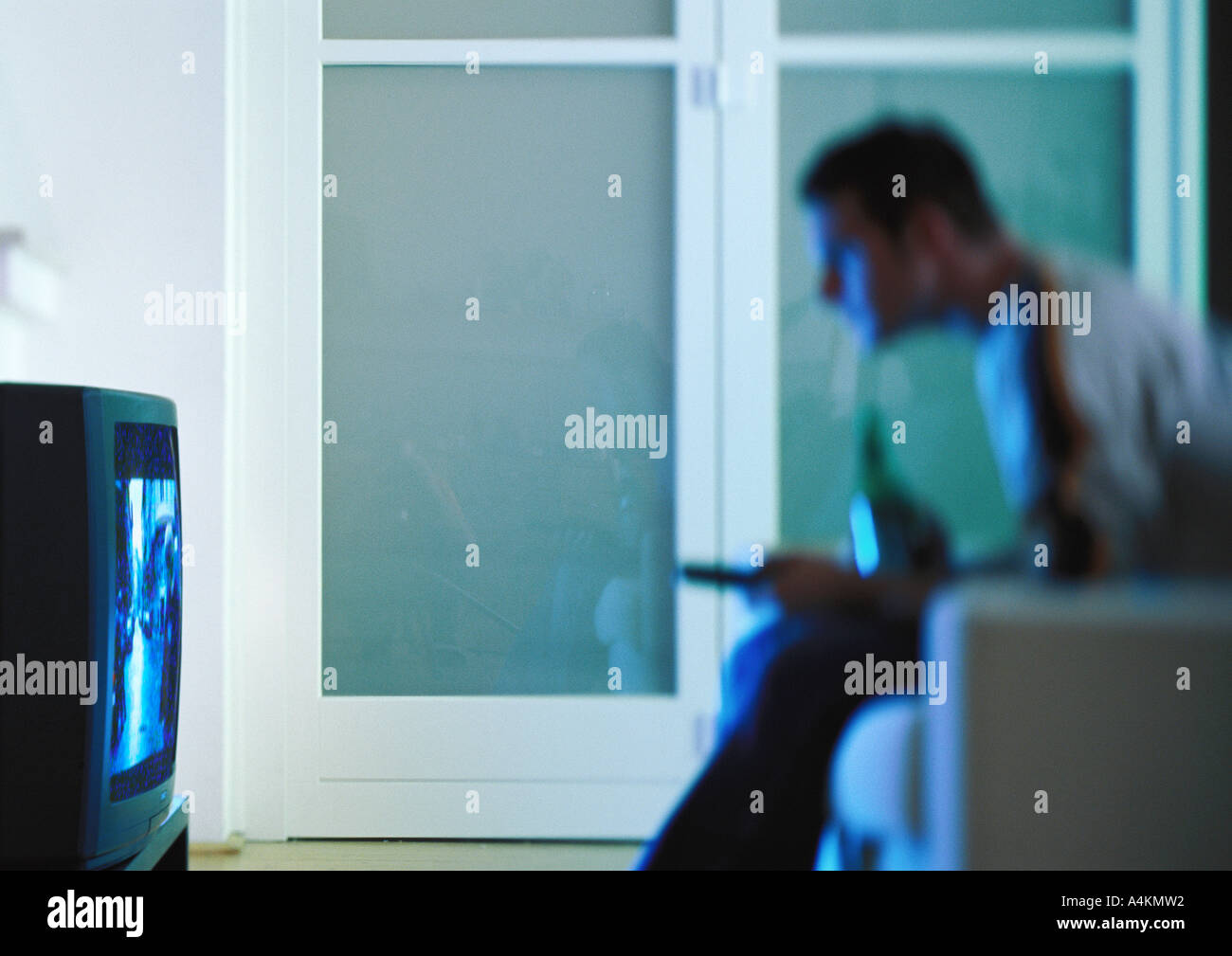 Man with beer watching television, side view, blurred Stock Photo
