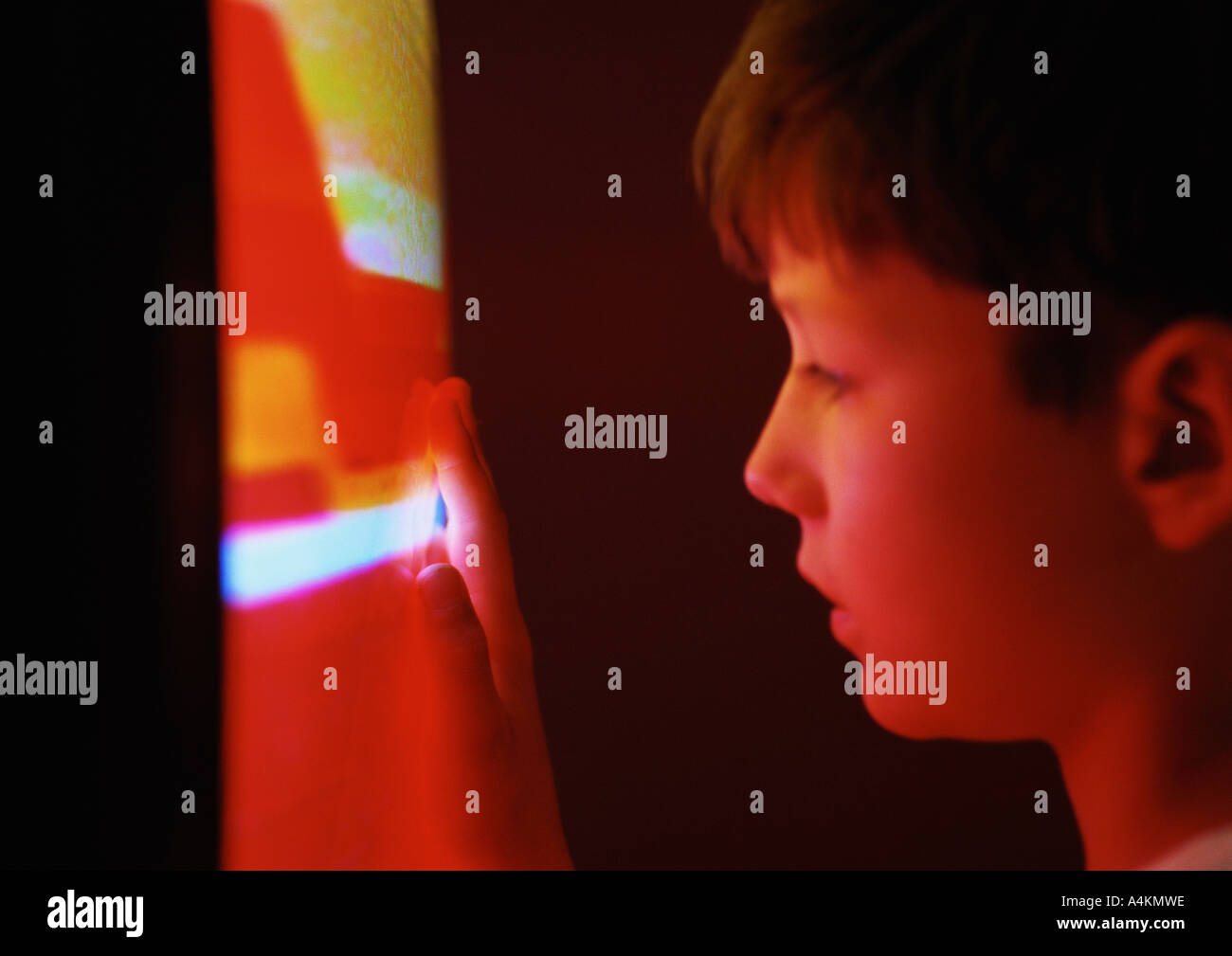 Little boy, face held close to television, hand touching glowing screen Stock Photo