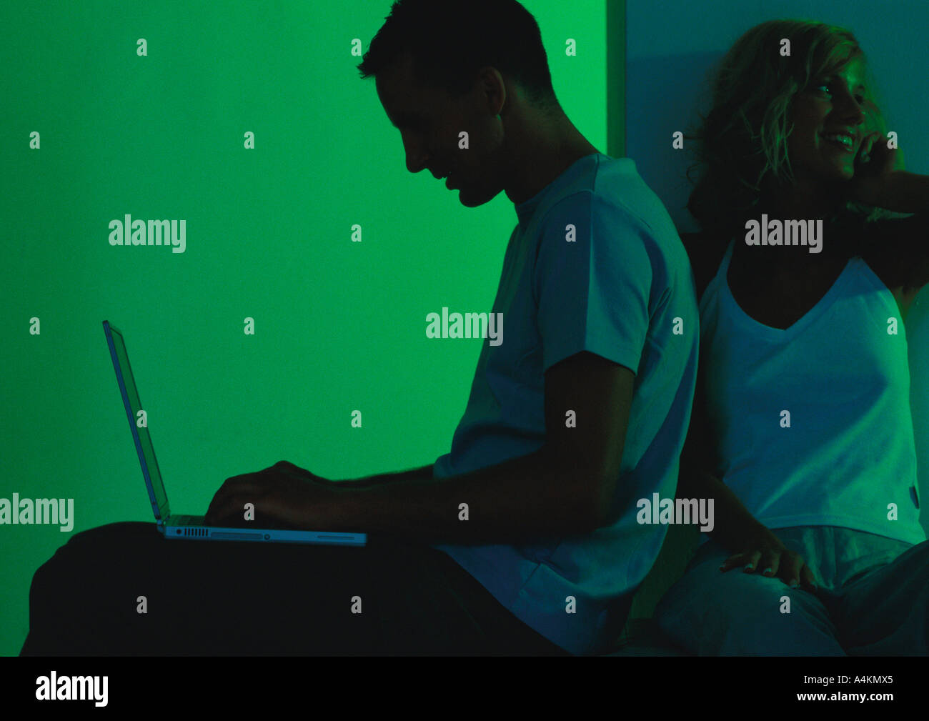 Man using laptop, woman sitting behind him Stock Photo