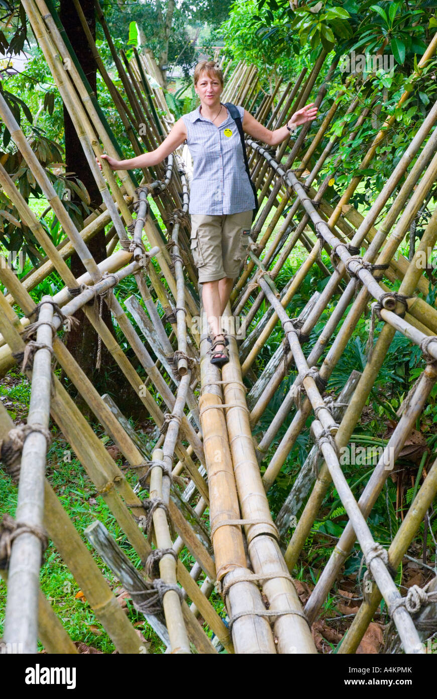 A Canadian woman tourist negotiates a bamboo bridge at the Sarawak Cultural Village in Malaysia Stock Photo