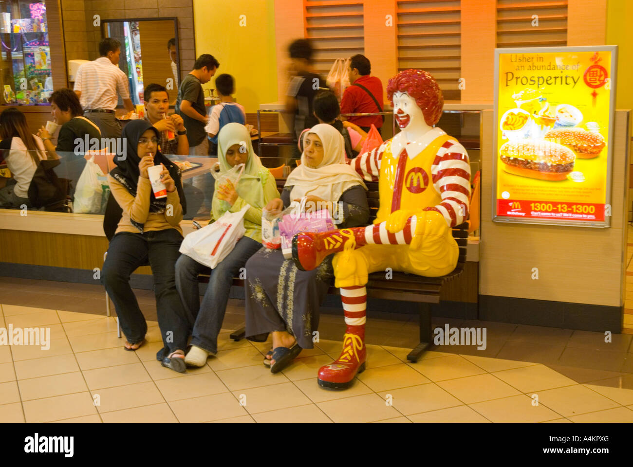 Muslim women and Ronald McDonald clown in a shopping mall in Malaysia Stock Photo