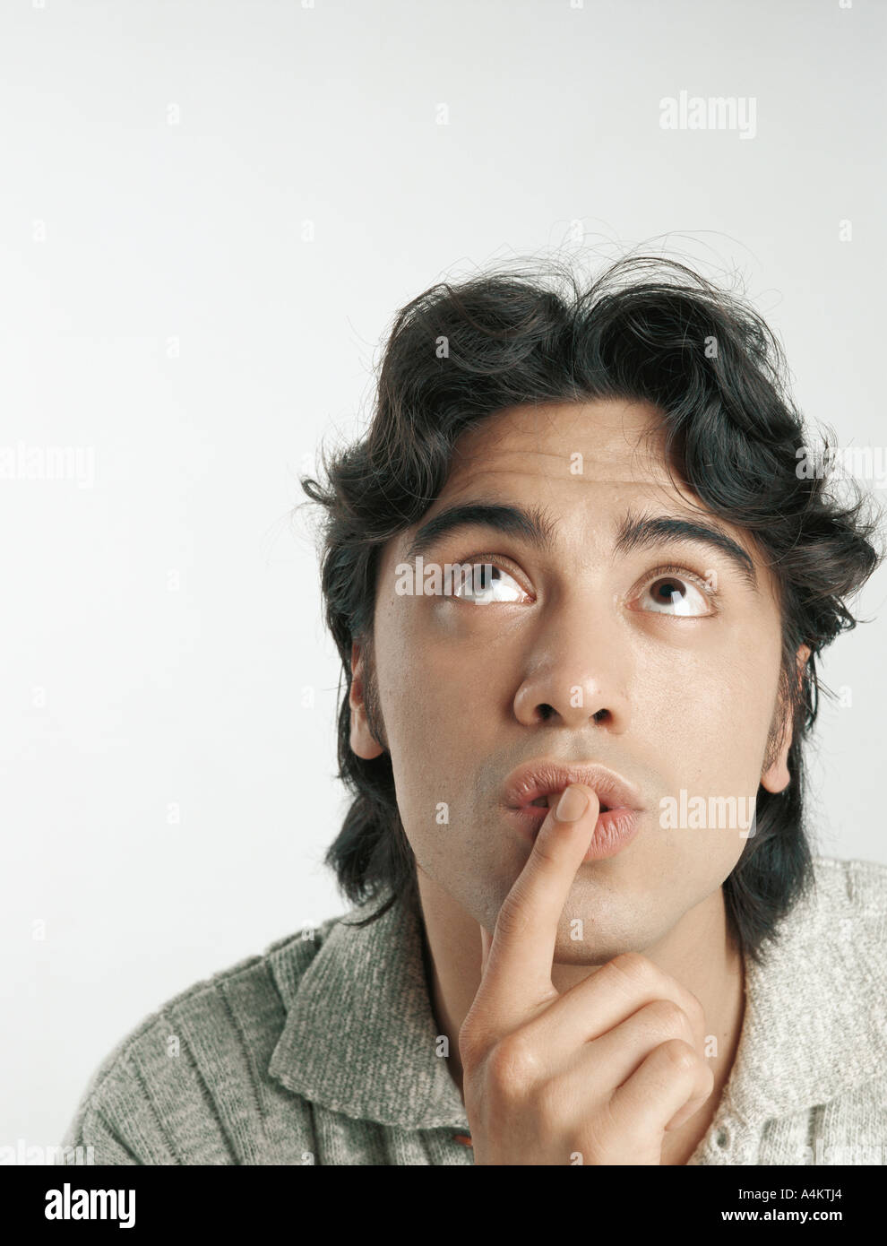 Man looking up with finger on lips Stock Photo