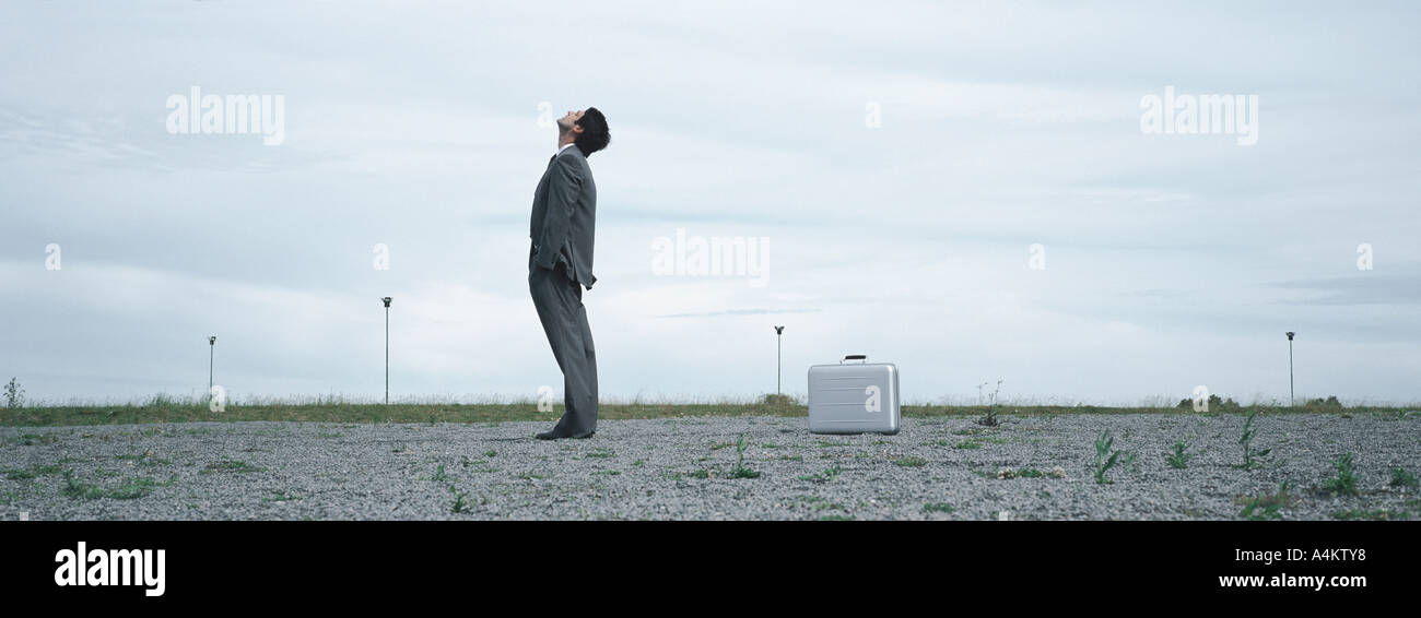 Man Standing In Abandoned Lot Looking Up At Sky Metallic