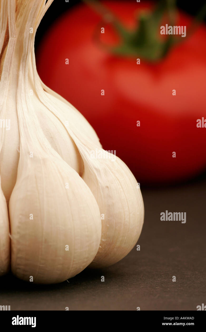 Single garlic clove and tomato on black background Stock Photo - Alamy
