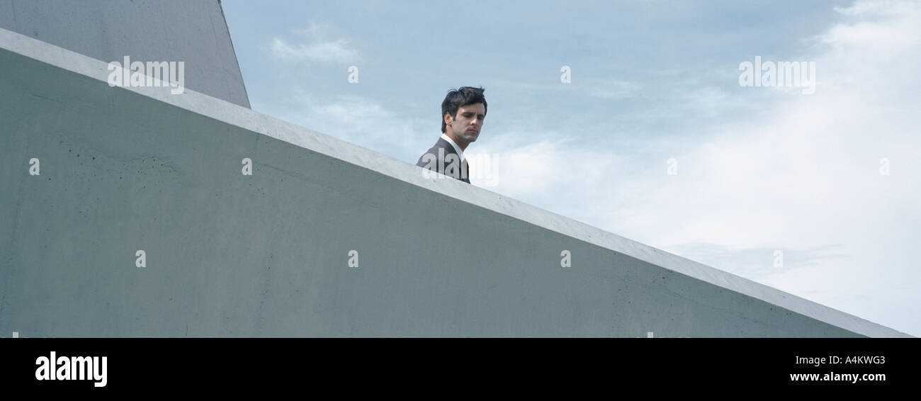 Man standing behind concrete wall, low angle view Stock Photo