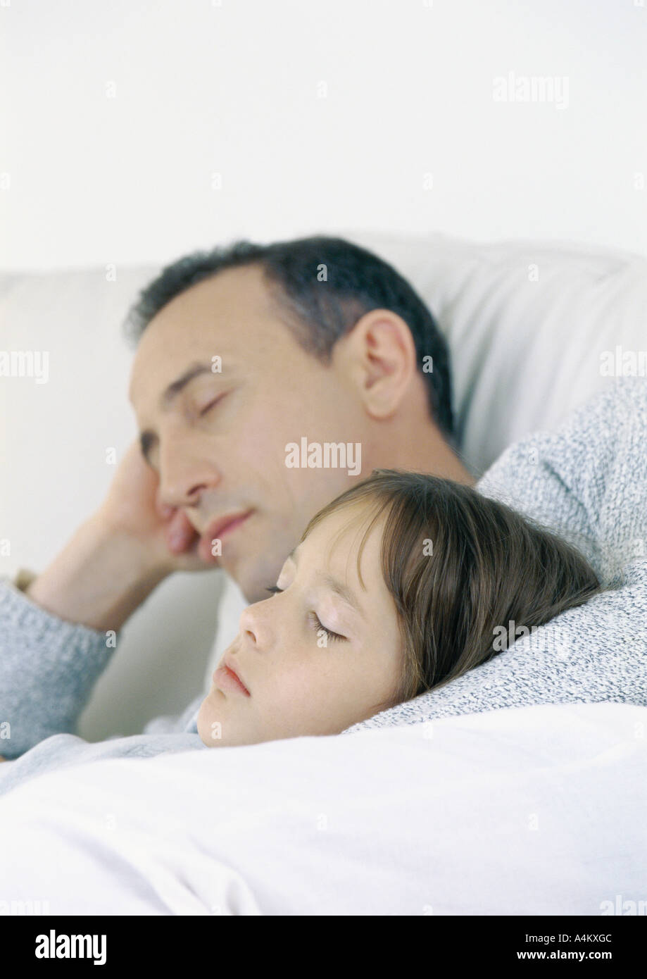 Father and daughter sitting on sofa, sleeping Stock Photo