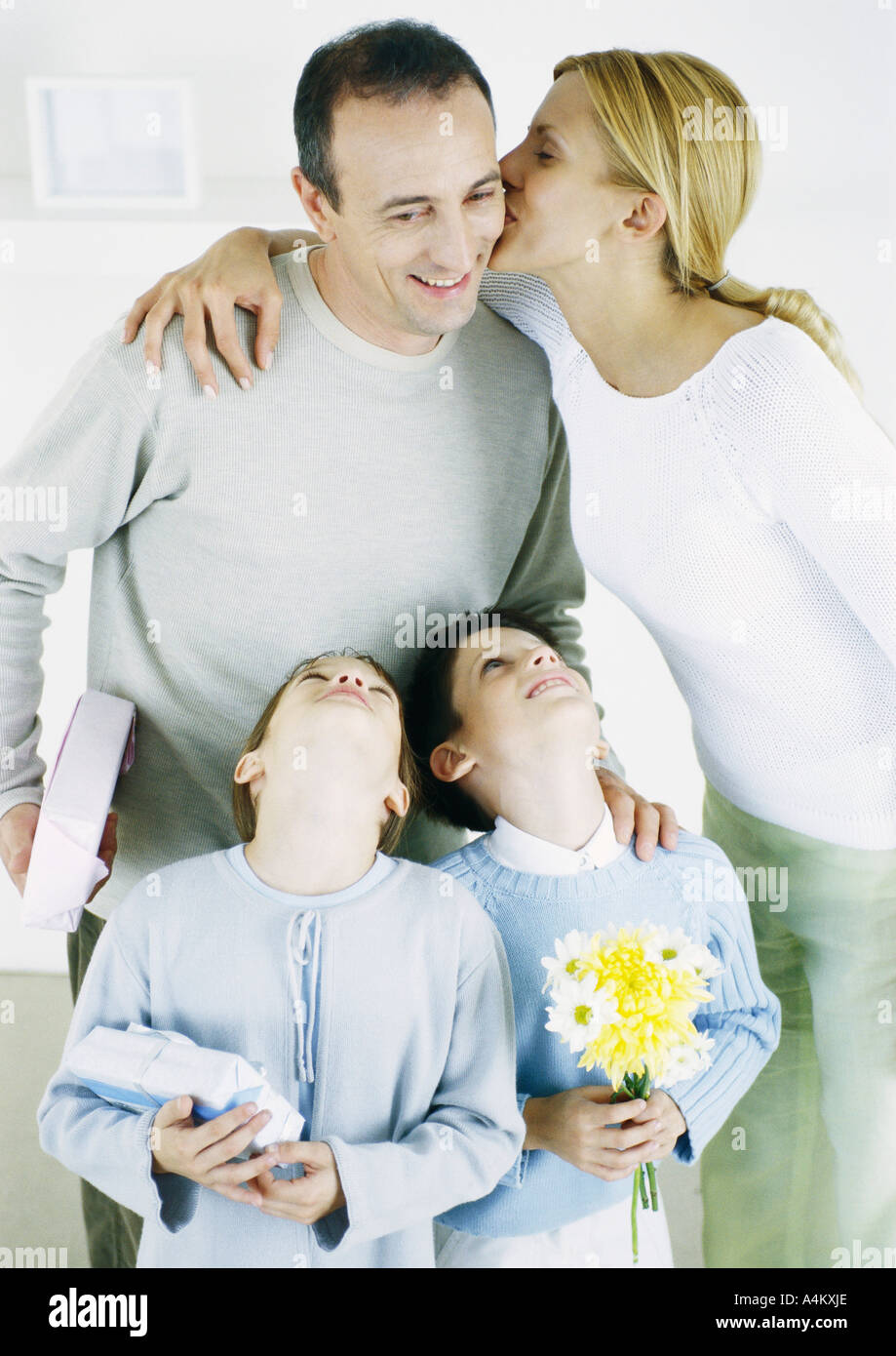 Woman kissing man on cheek, girl and boy looking up with heads back Stock Photo