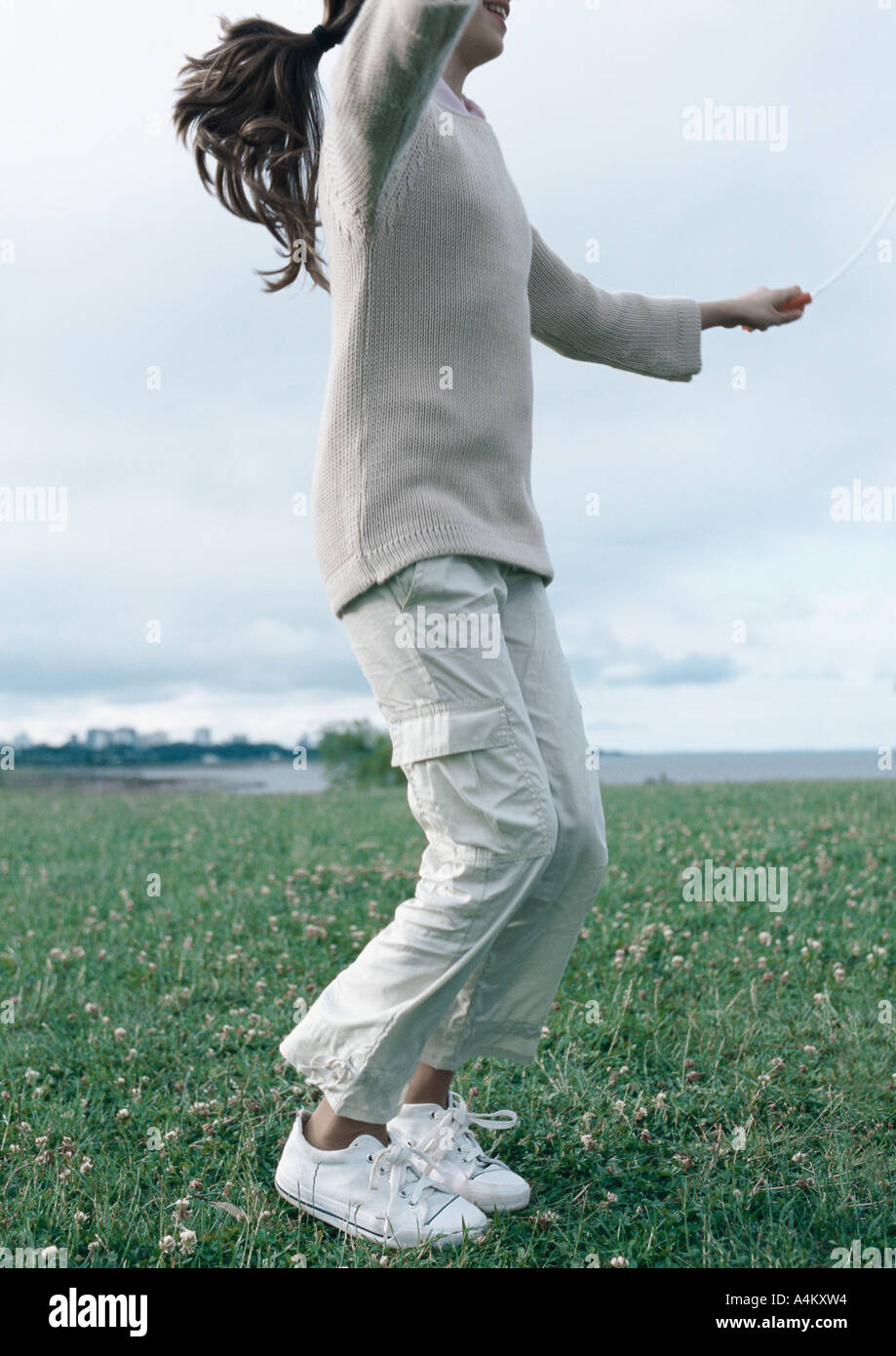 Girl jumping rope on grass Stock Photo Alamy
