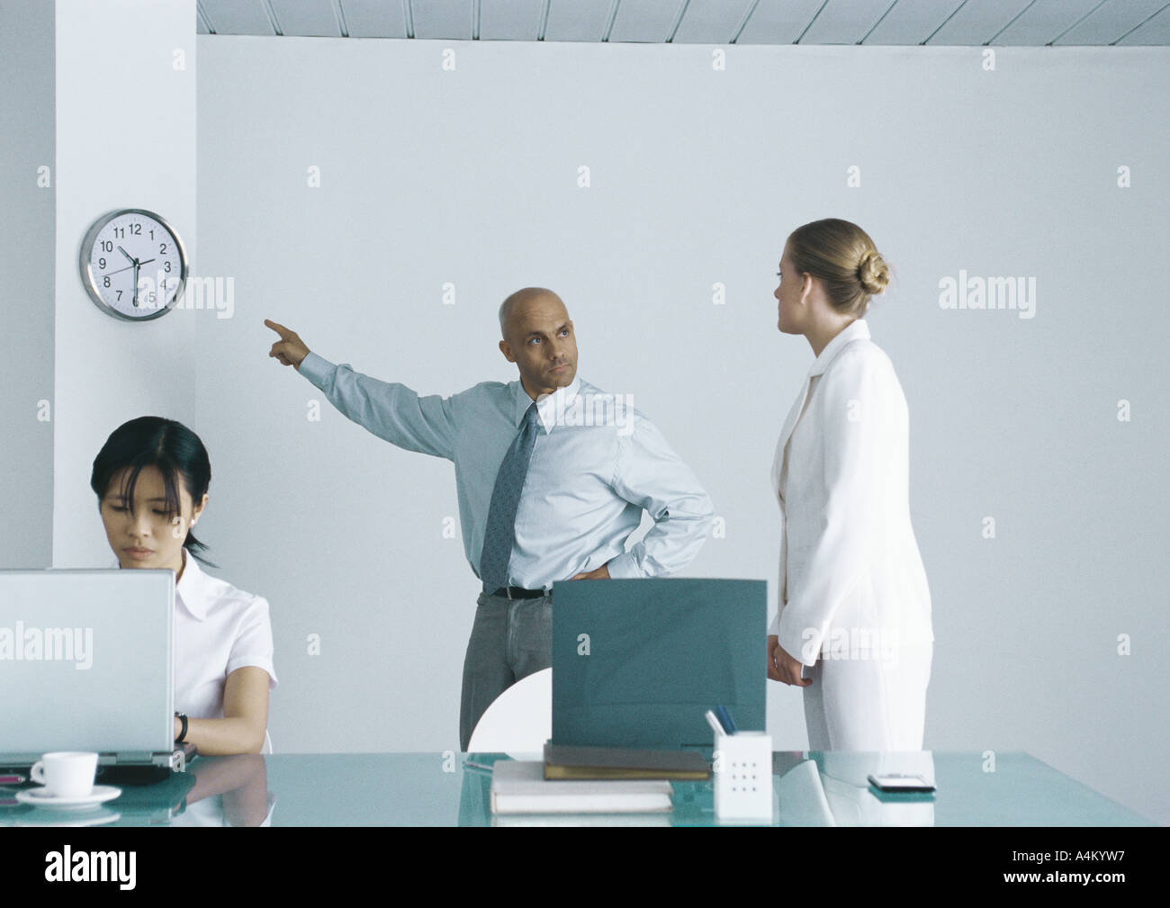Boss pointing at clock and looking sternly at employee Stock Photo Alamy