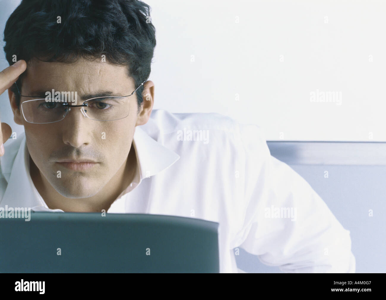 Businessman looking at computer, furrowing brow Stock Photo