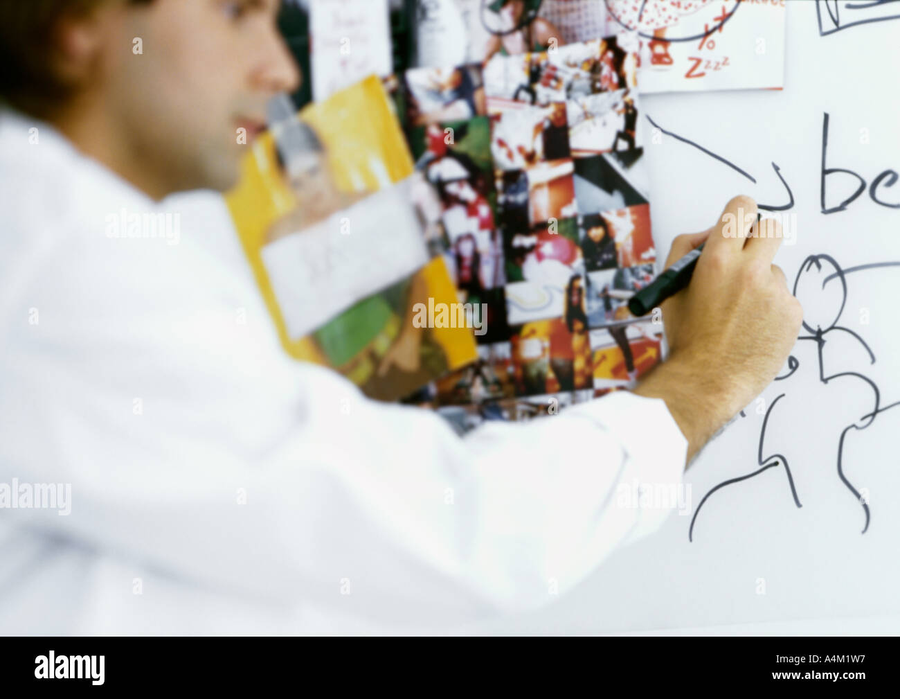 Man writing on board with images taped to it Stock Photo