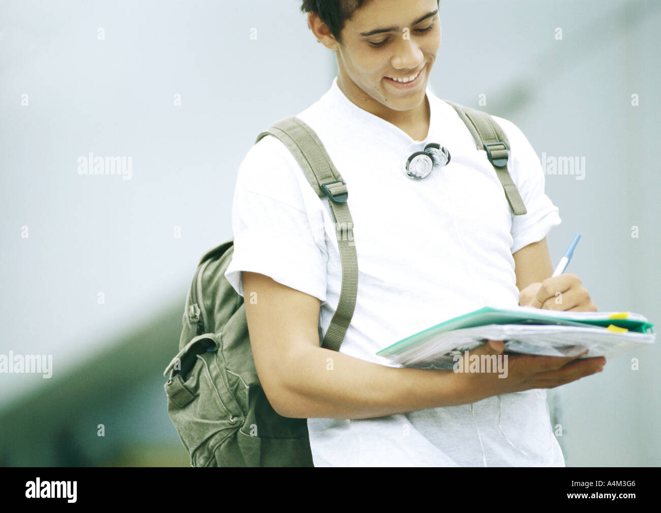 Male student standing and writing on folder Stock Photo