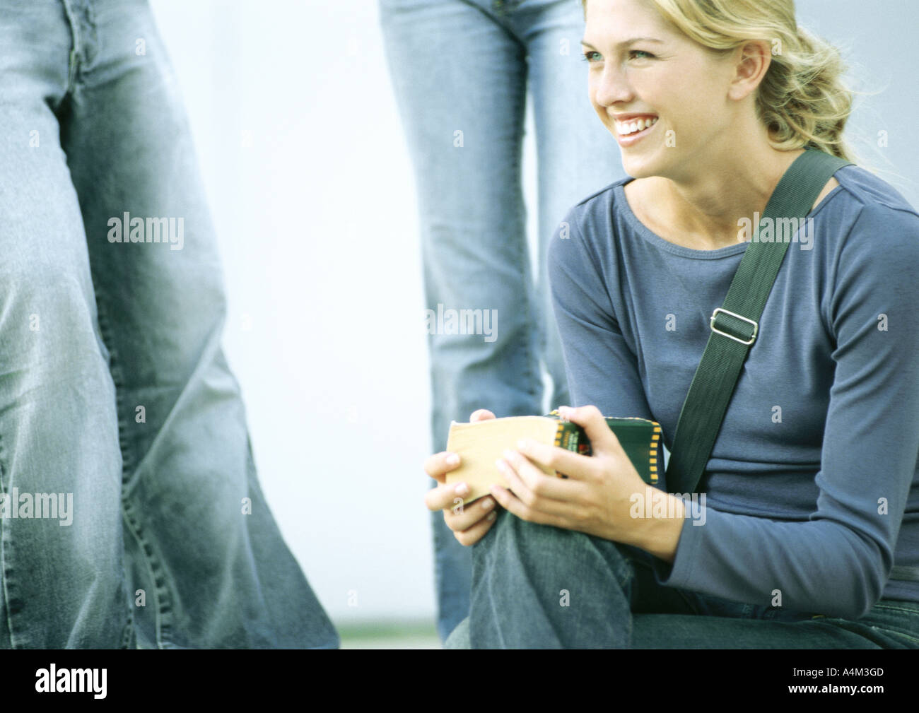 Student sitting and smiling, other students standing in background Stock Photo