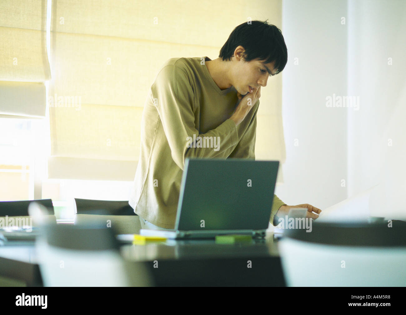 Young man using phone and laptop Stock Photo