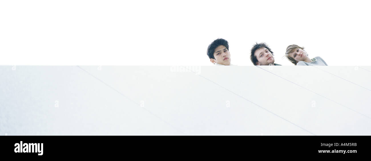 Young people at rooftop edge looking down, low angle view Stock Photo