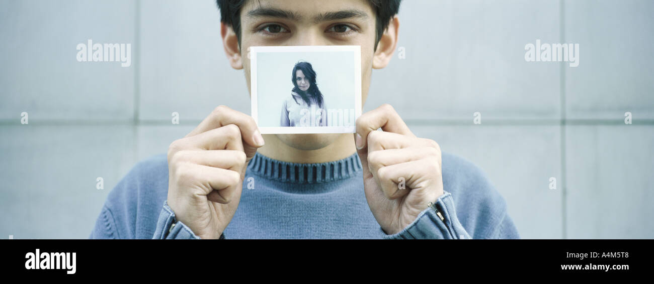 Young man holding up photo of young woman Stock Photo
