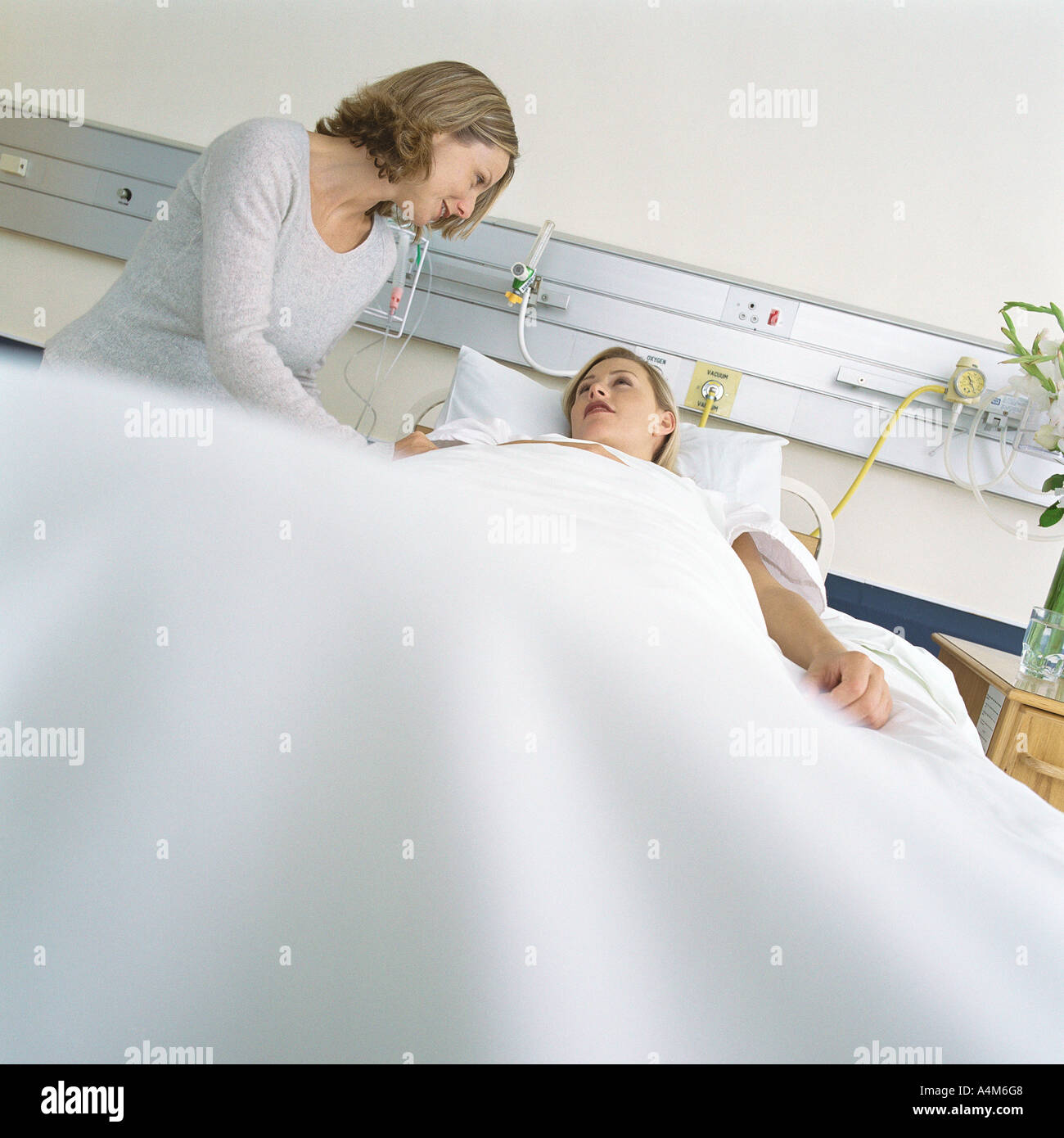 Visitor talking to patient in hospital bed Stock Photo