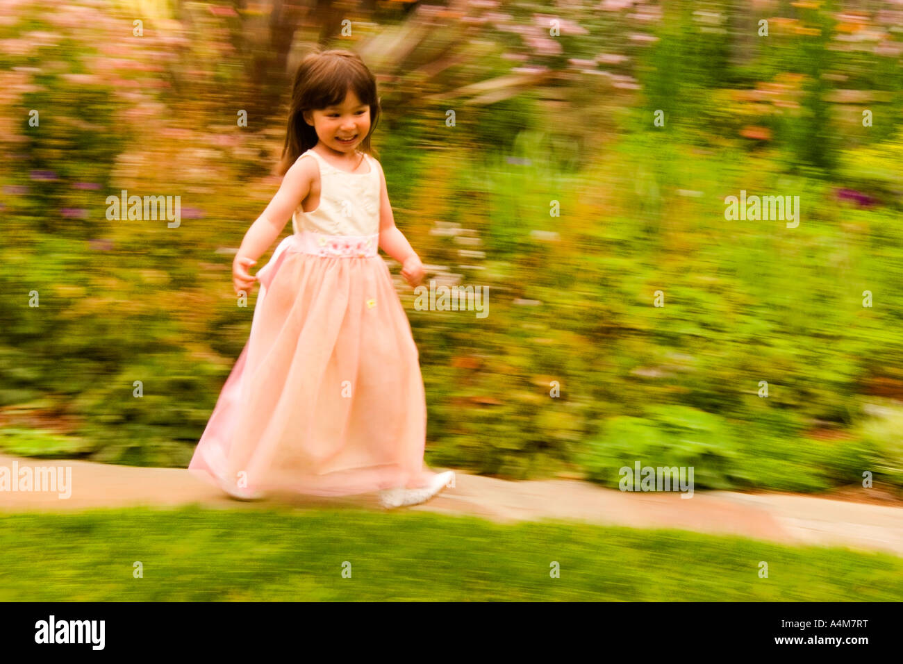A little girl in a pink dress runs along a garden path Stock Photo - Alamy