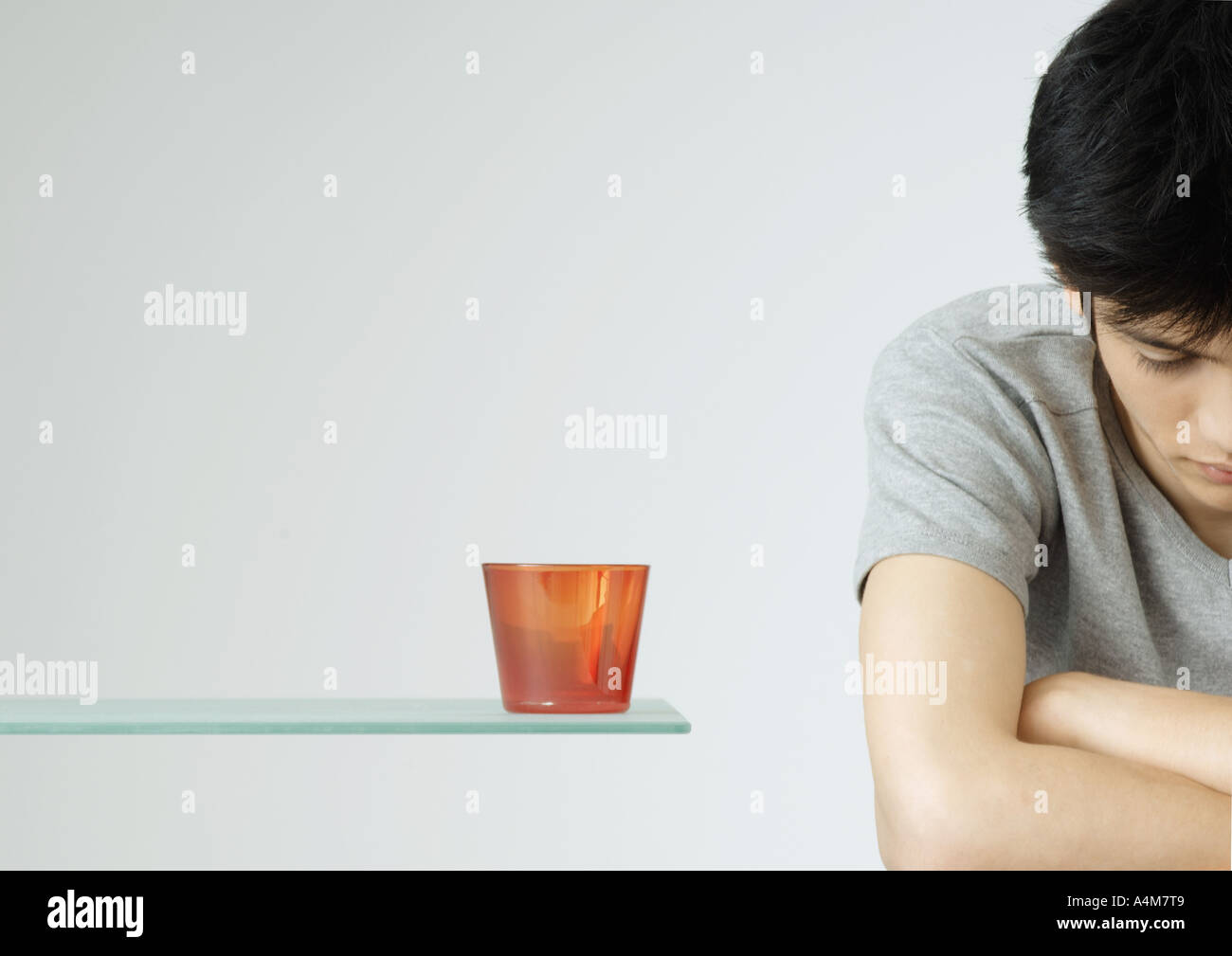 Young man with arms folded and head down Stock Photo