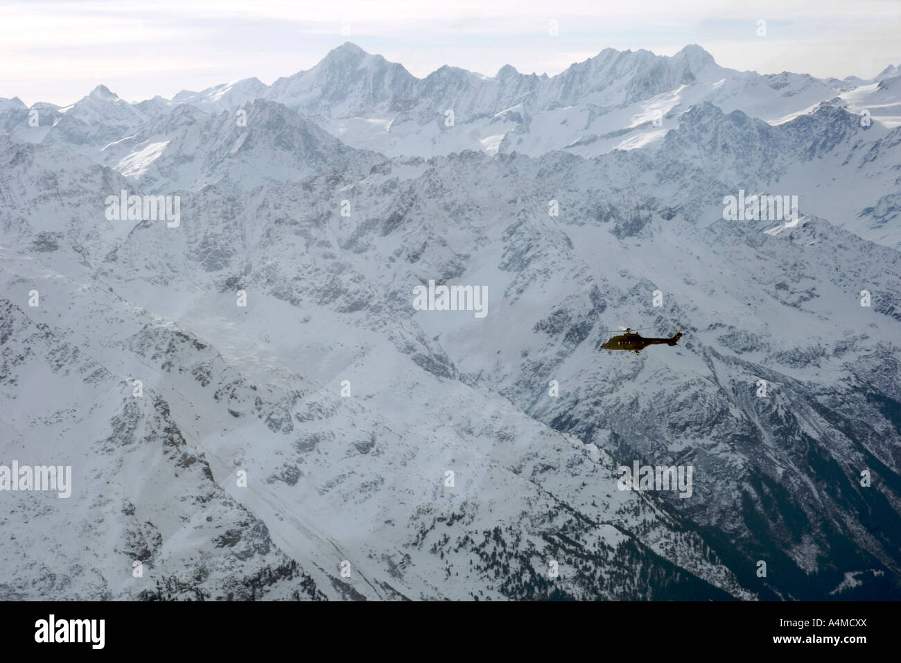 A helicopter seen flying across the Alps from the summit of Mount Titlis in Switzerland. Stock Photo