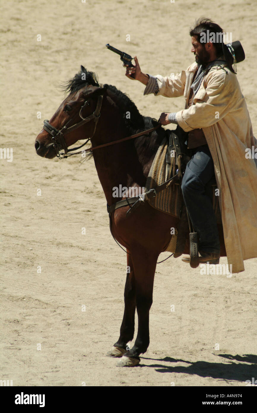 Cowboy on a horse shooting a gun Stock Photo