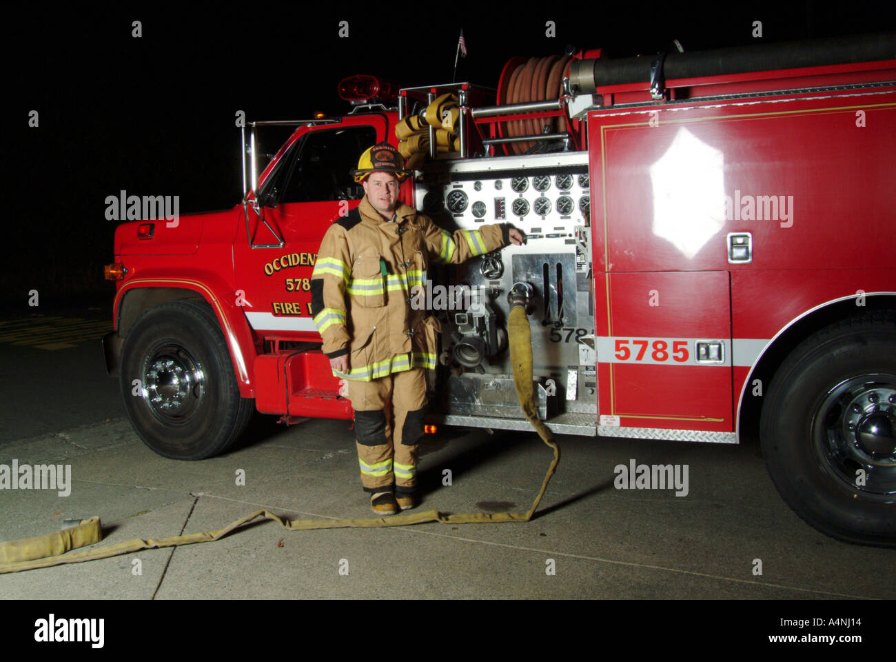A fire fighter stands next to a fire engine with the Occidental Volunteer Fire Department Occidental California MR L 022p Stock Photo