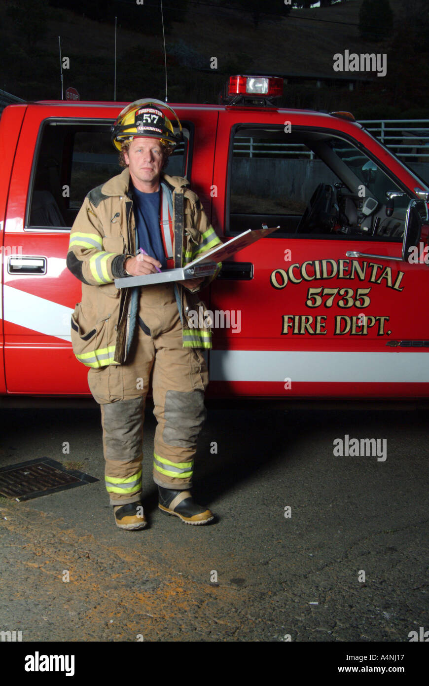 A fire fighter stands next to a fire engine with the Occidental Volunteer Fire Department Occidental California MR L 022n Stock Photo