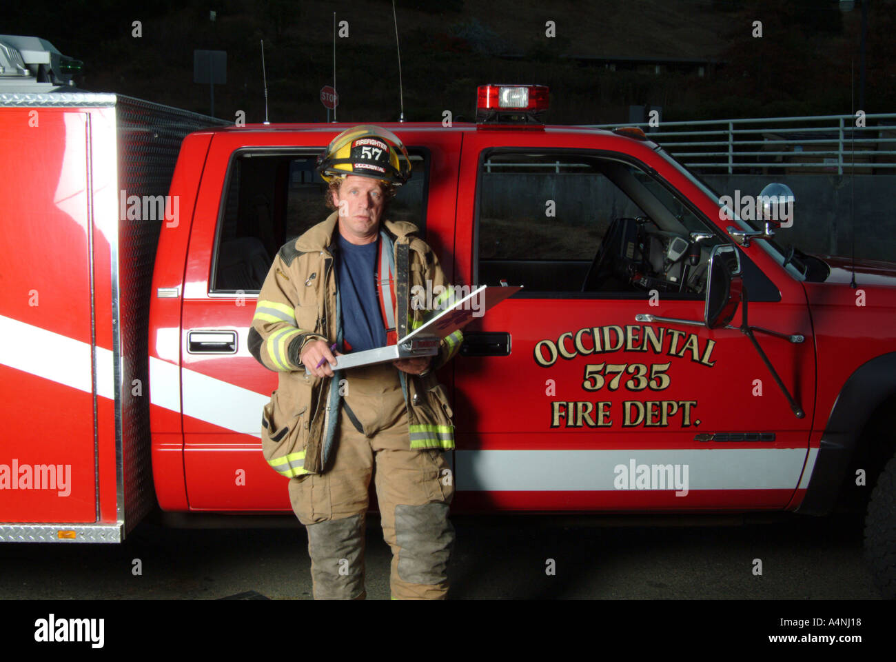 A fire fighter stands next to a fire engine with the Occidental Volunteer Fire Department Occidental California MR L 022n Stock Photo