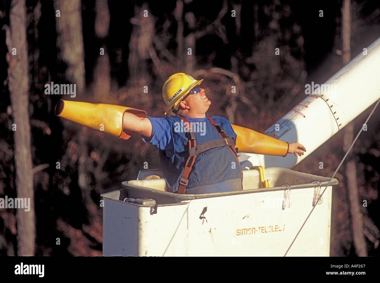 Electrical Lineman working on power lines on poles with safety