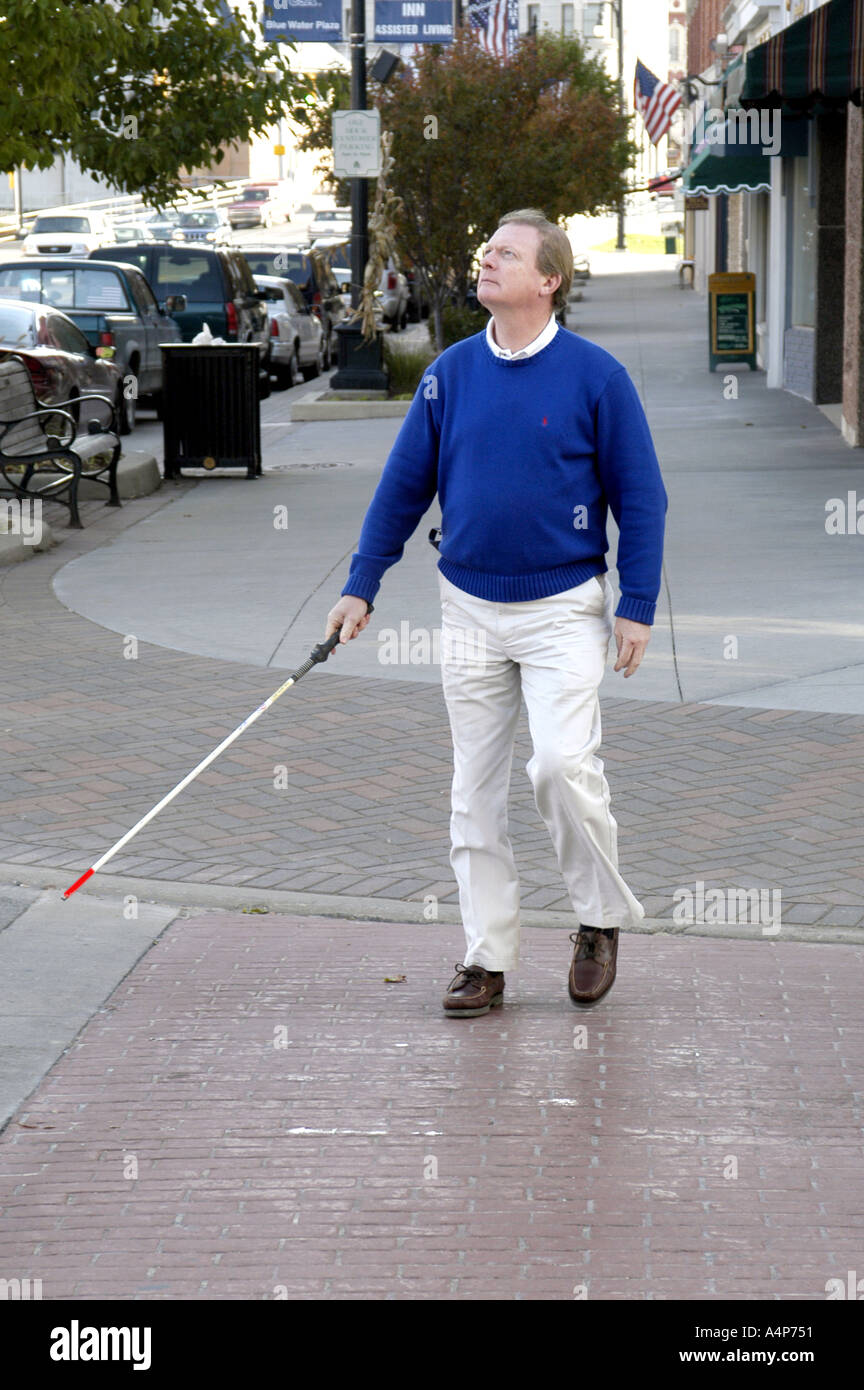 Young blind man in dark glasses walking with a cane stick on the