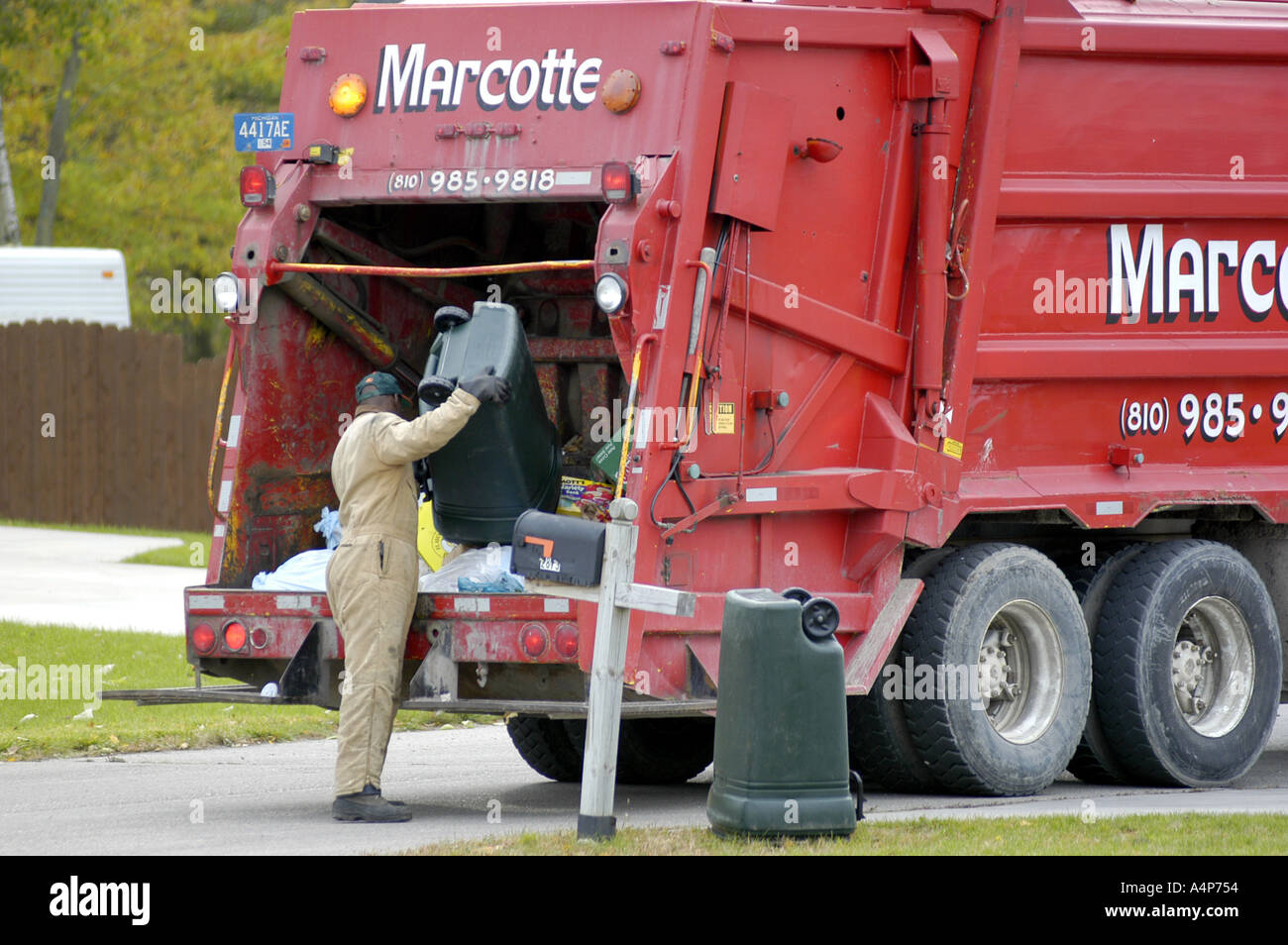 Garbage truck picks up trash refuse in a residential neighborhood Stock