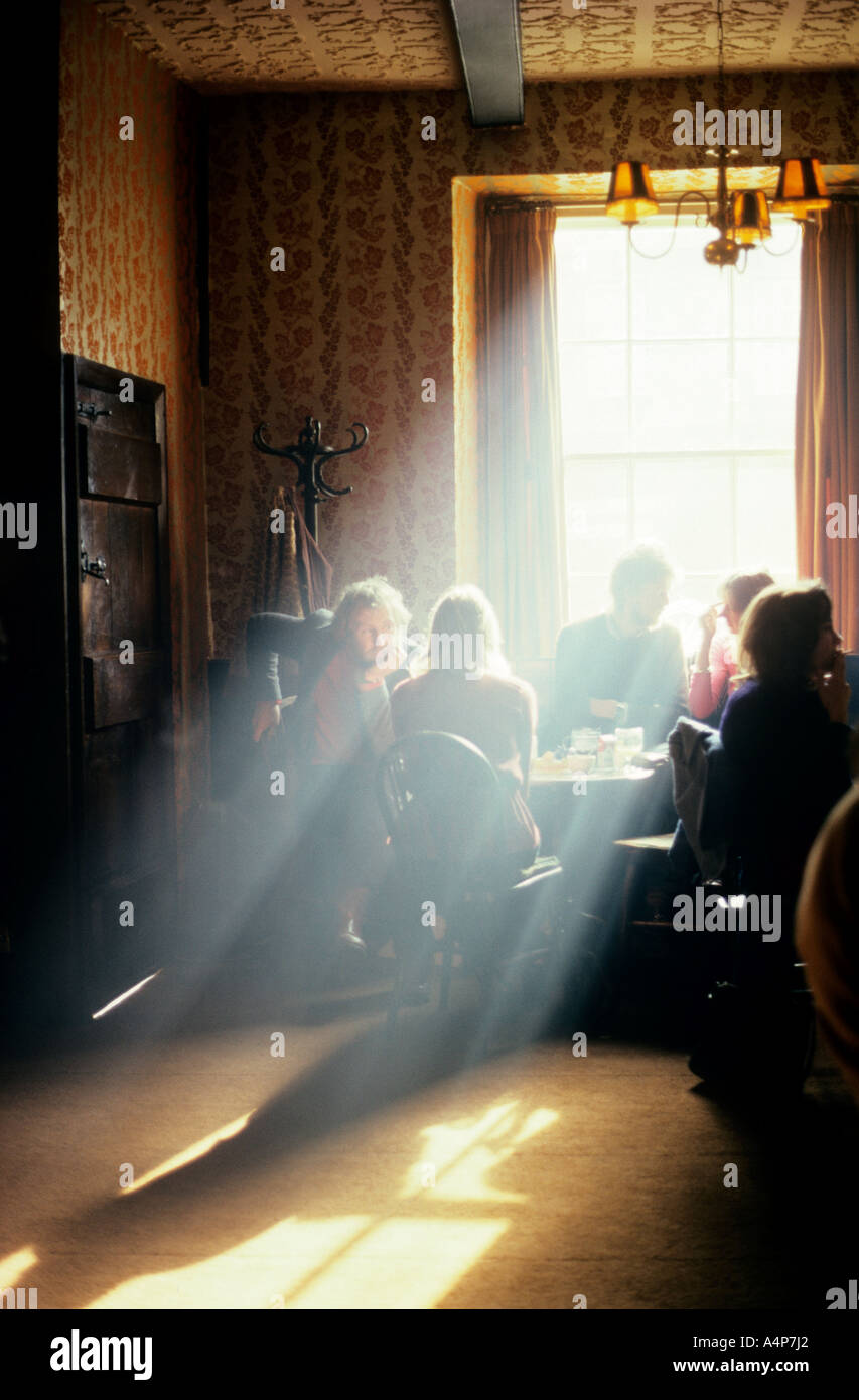 Light streaming through window of an old traditional public house with people sitting drinking England UK Stock Photo