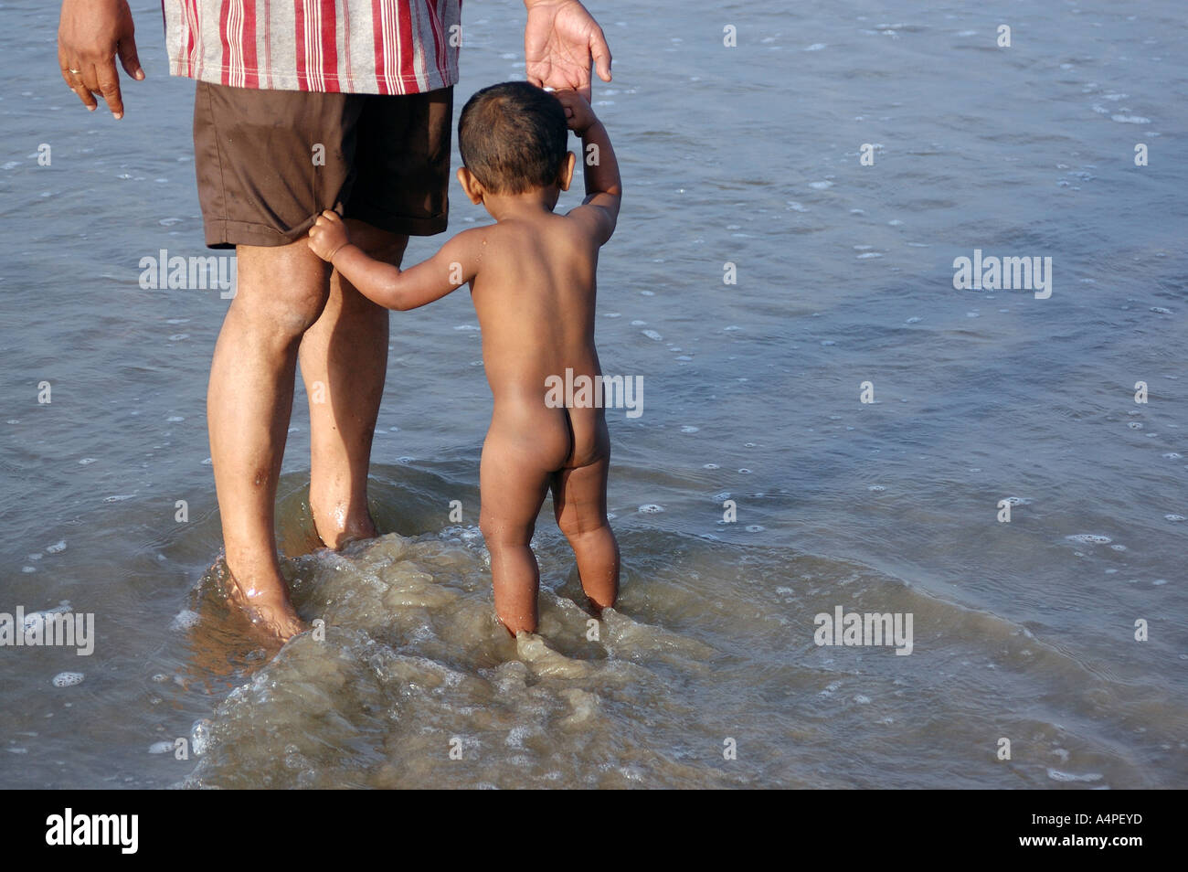 ANG77700 Indian Child and Grand father standing in sea water Goa India Stock Photo