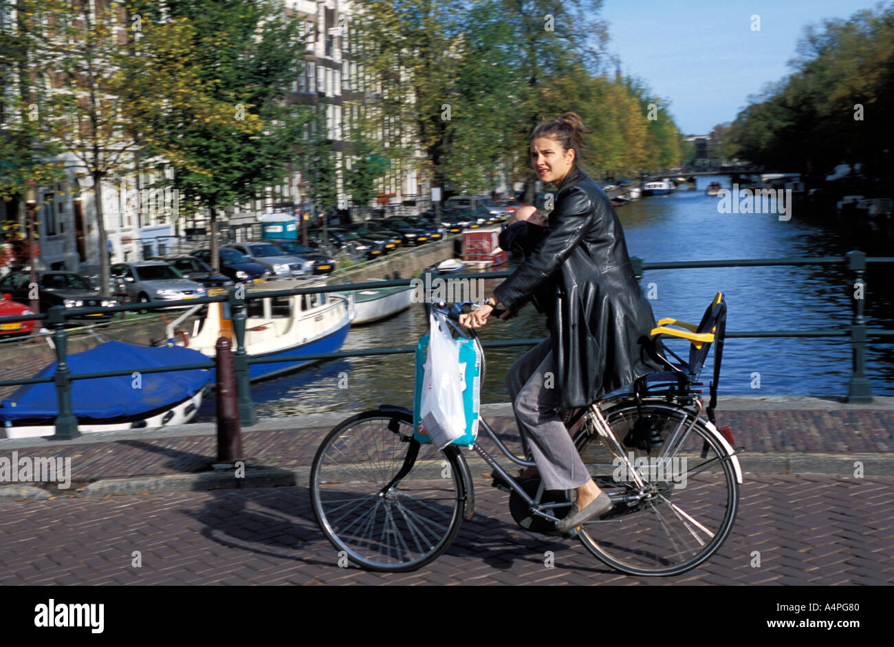 A Dutch woman with her baby cycling along Kaizersgracht canal Amsterdam The Netherlands Holland Europe Stock Photo
